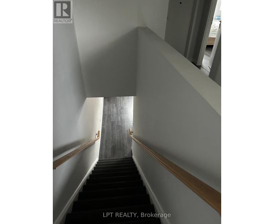 A staircase with a wooden handrail and black steps.