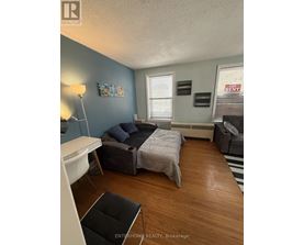 A bedroom with a bed, couch, and chair.