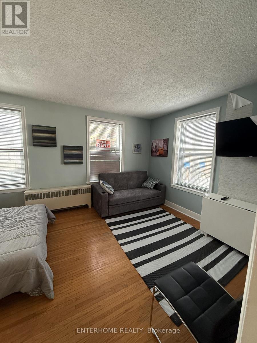 A bedroom with a bed, a couch, and a striped rug.