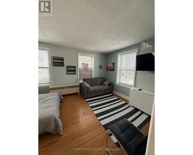 A bedroom with a bed, a couch, and a striped rug.