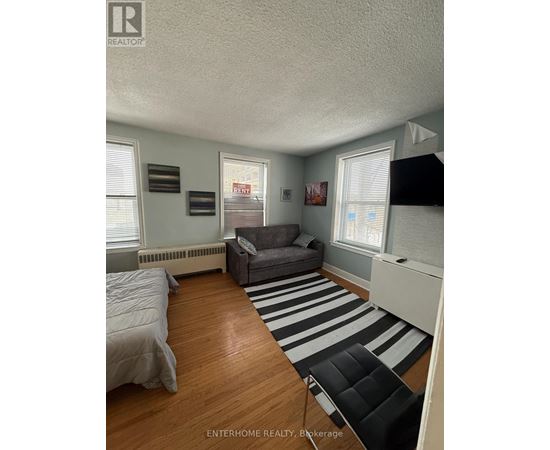 A bedroom with a bed, a couch, and a striped rug.
