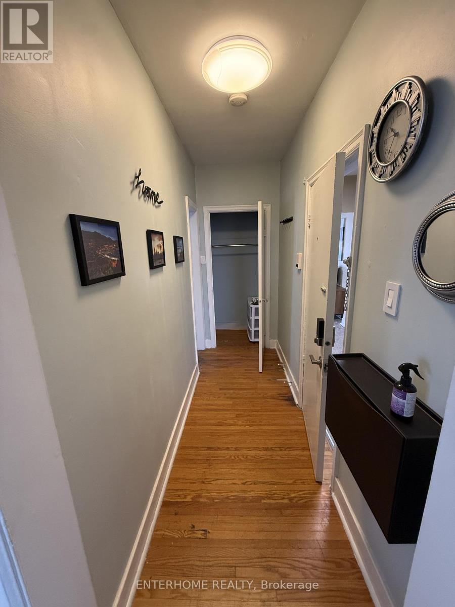A hallway with a clock on the wall and a wooden floor.