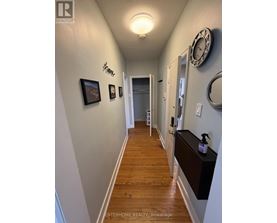 A hallway with a clock on the wall and a wooden floor.