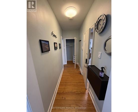 A hallway with a clock on the wall and a wooden floor.