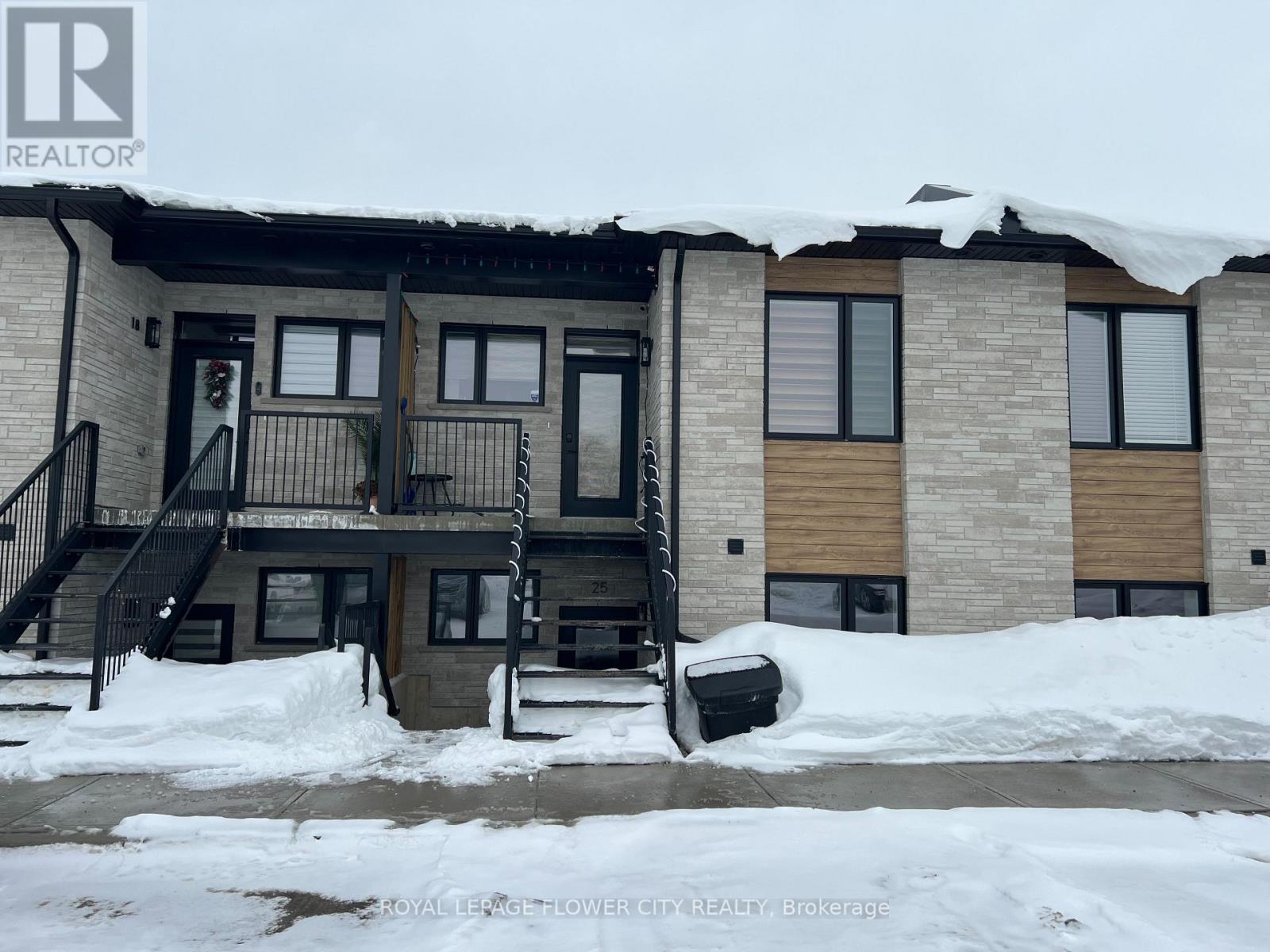 A building with a snow-covered roof and a black trash bin in front.