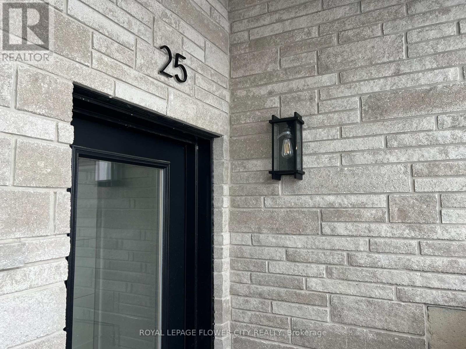 A black door with a glass window is on a brick wall with a number 25 above it.