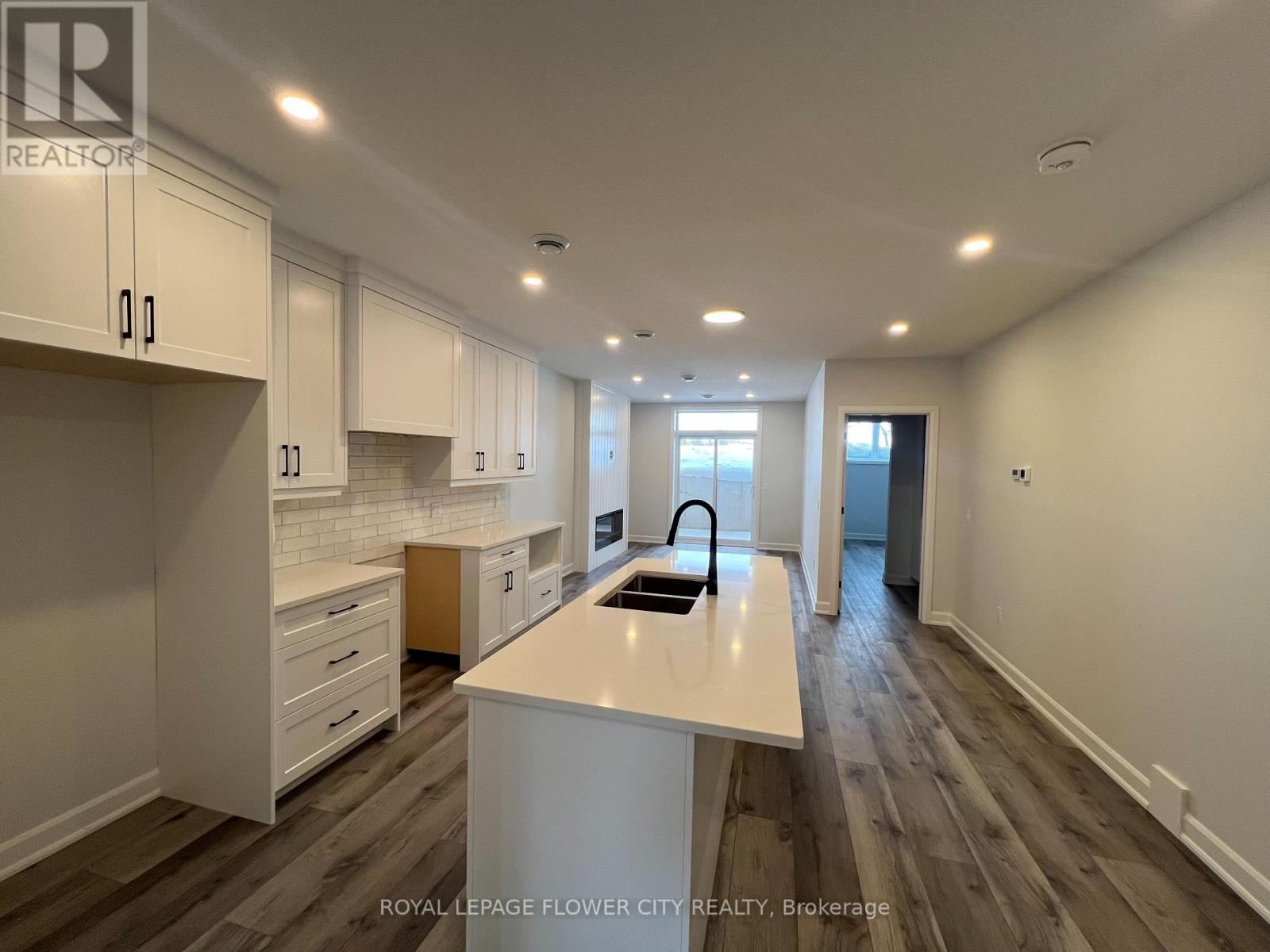 A kitchen with white cabinets and a white island with a sink.