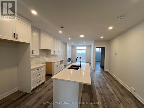 A kitchen with white cabinets and a white island with a sink.