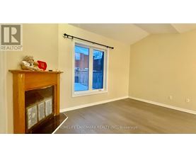 A room with a fireplace and a window with a view of a fence and buildings outside.