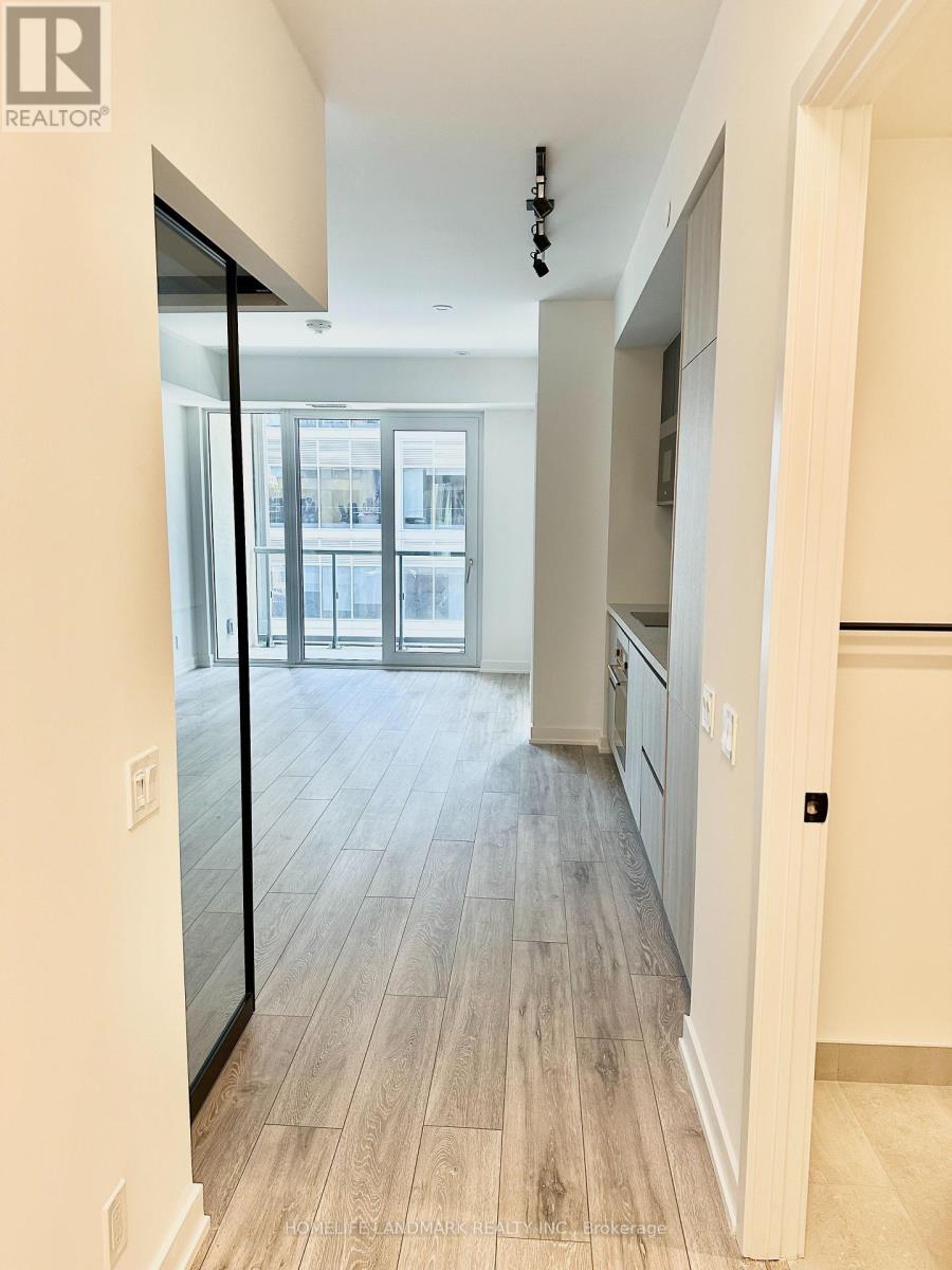A hallway with a wooden floor leads to a kitchen area.