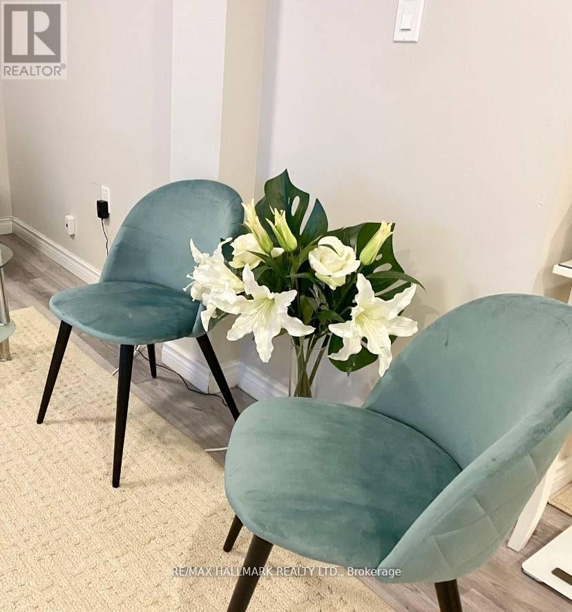 Two chairs and a vase with white flowers on a carpeted floor.