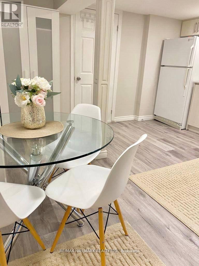 A glass table with a vase of flowers on it and four chairs around it.