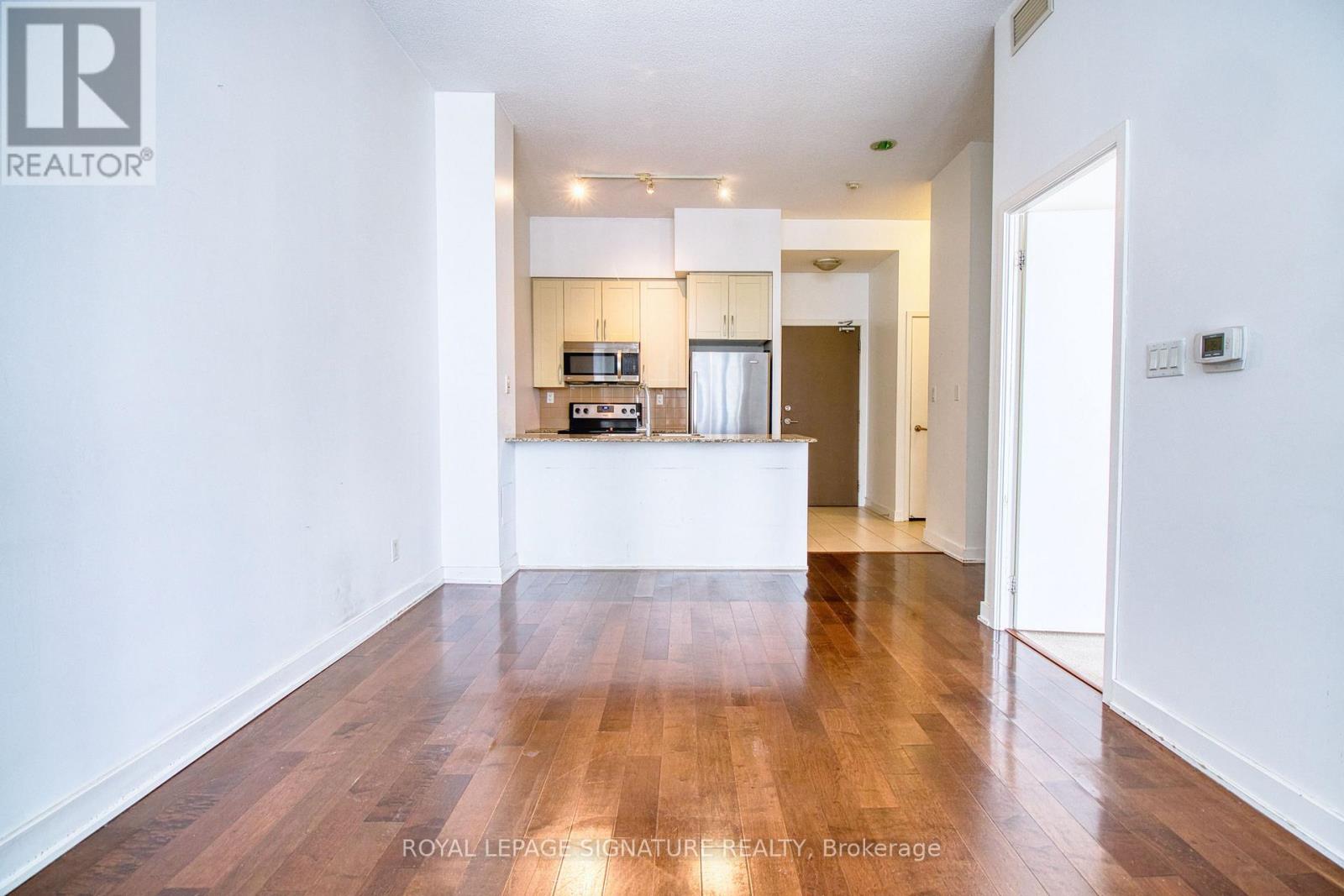 A spacious room with wooden flooring and white walls.