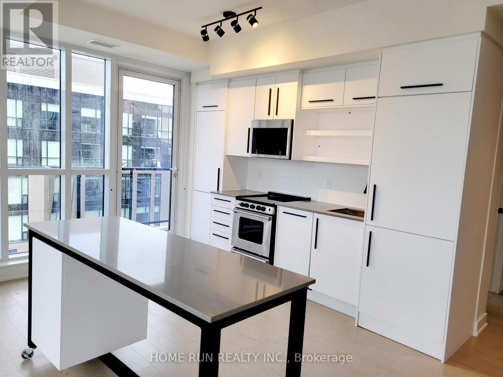 A kitchen with white cabinets and a black island.