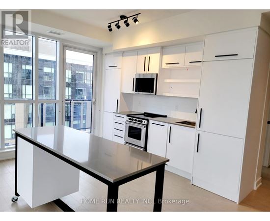 A kitchen with white cabinets and a black island.