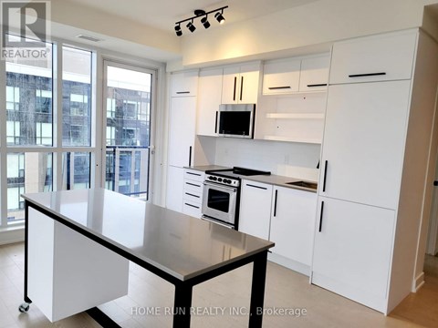 A kitchen with white cabinets and a black island.