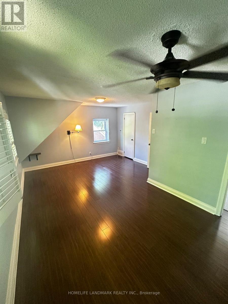 A room with a ceiling fan and wooden floors.
