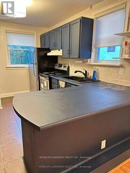 A kitchen with a black refrigerator and cabinets.