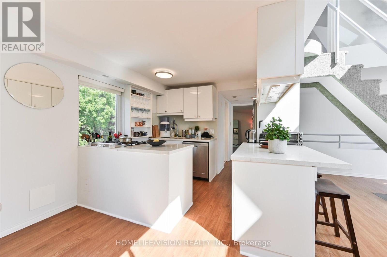 A modern kitchen with white cabinets and a wooden floor.