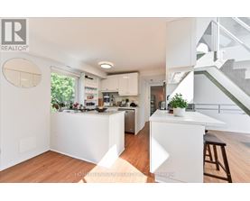 A modern kitchen with white cabinets and a wooden floor.