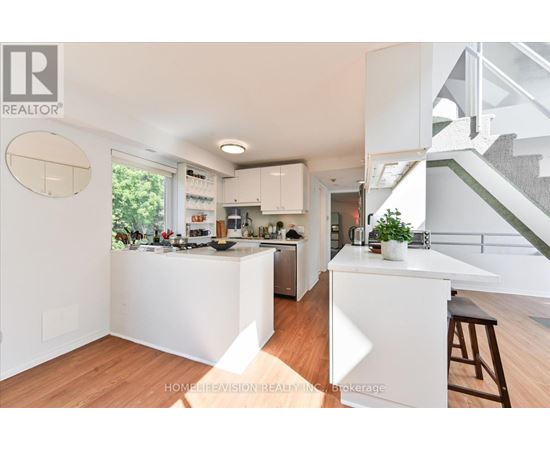 A modern kitchen with white cabinets and a wooden floor.