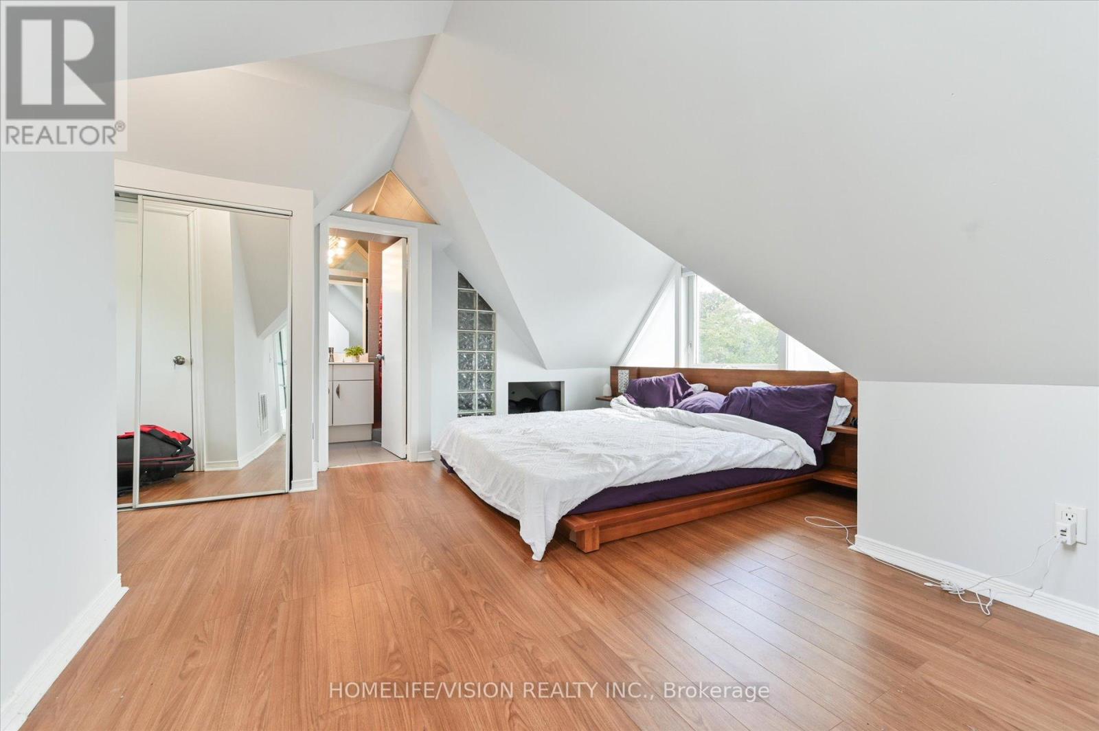 A bedroom with a bed, a couch, and a mirror.