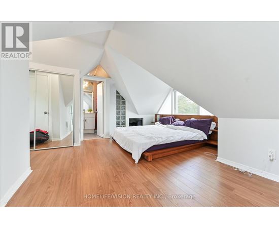 A bedroom with a bed, a couch, and a mirror.