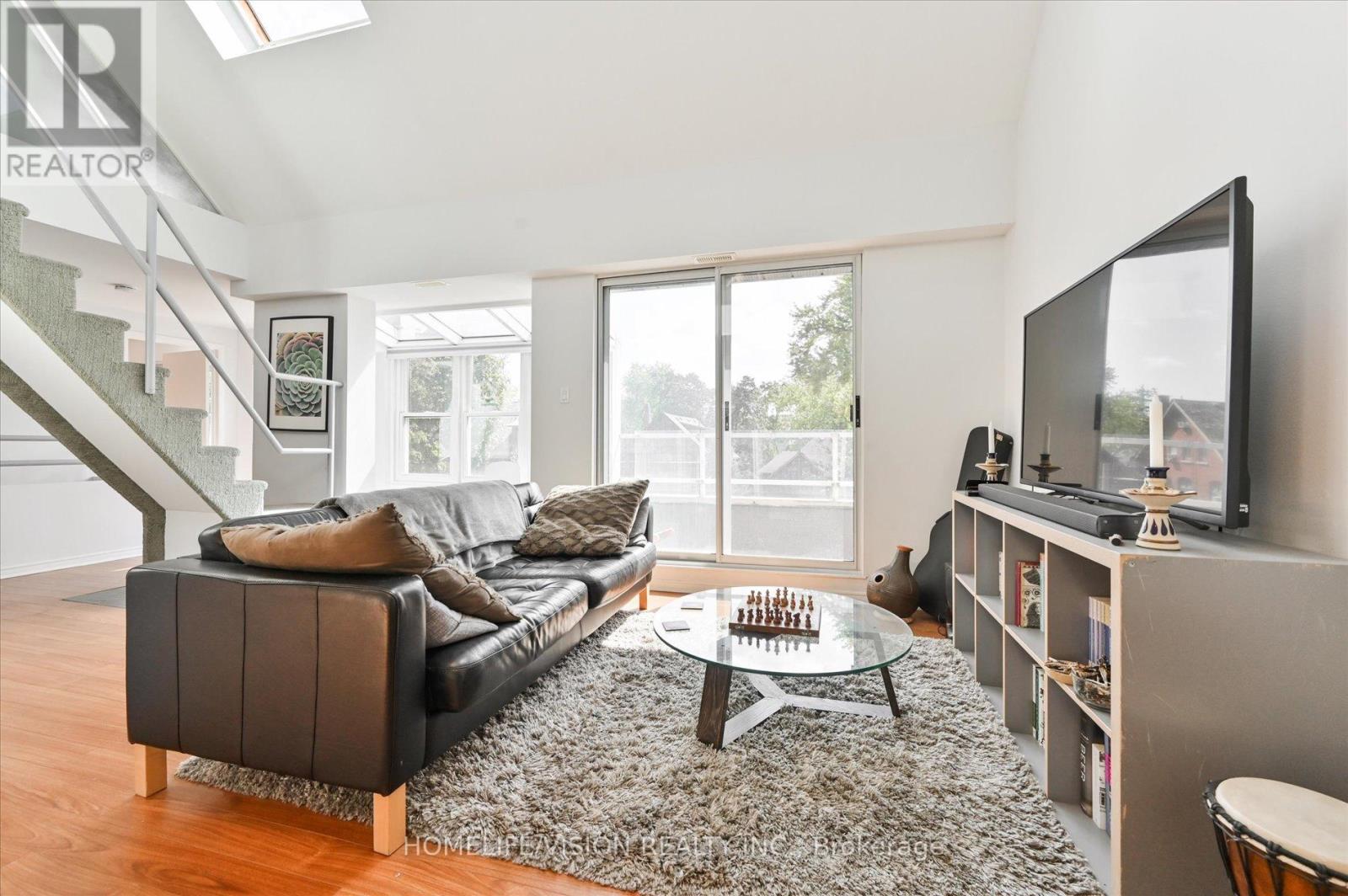 A living room with a black couch and a television on a stand.