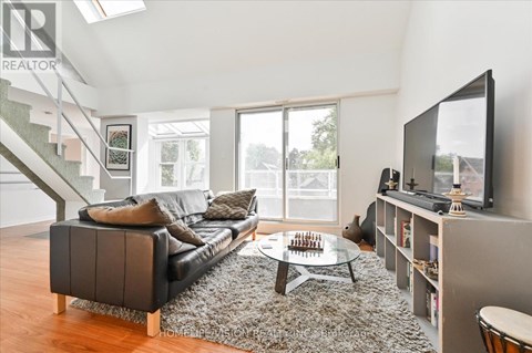 A living room with a black couch and a television on a stand.