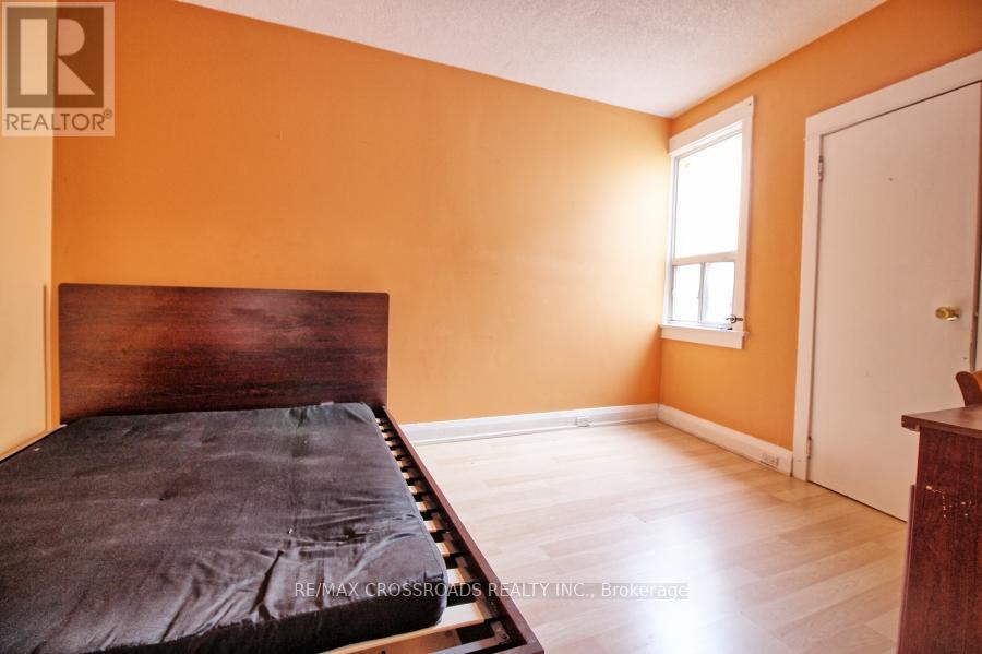 A bedroom with a bed, wooden headboard, and a window with white curtains.