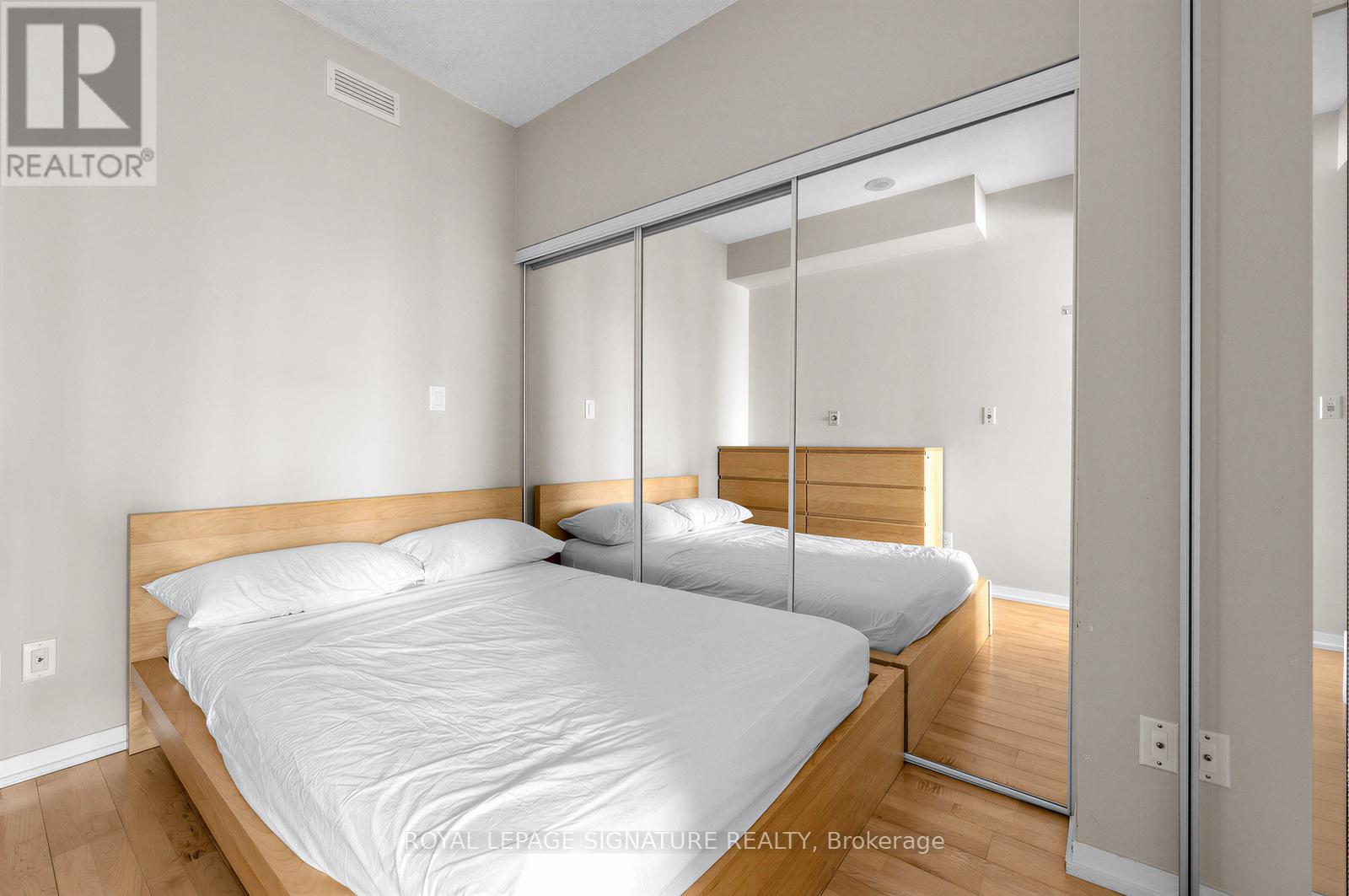 A bedroom with a large bed and a mirrored closet door.