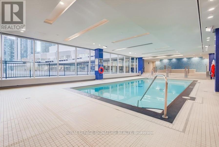 A large indoor swimming pool with a glass wall on one side.