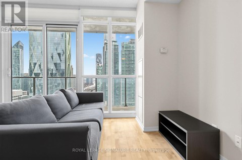 A living room with a grey couch and a large window overlooking a cityscape.