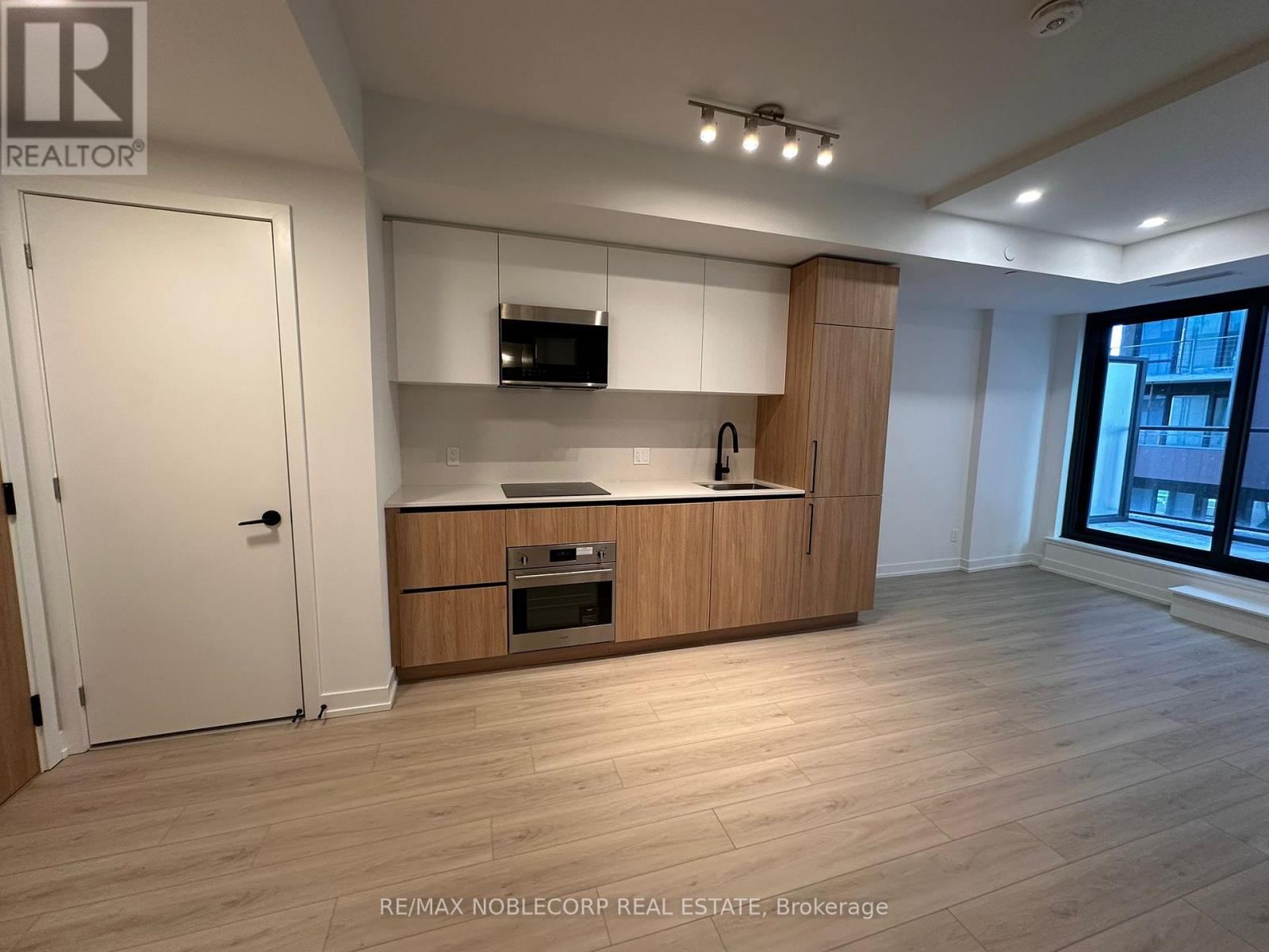 A spacious kitchen with wooden floors and a large window.