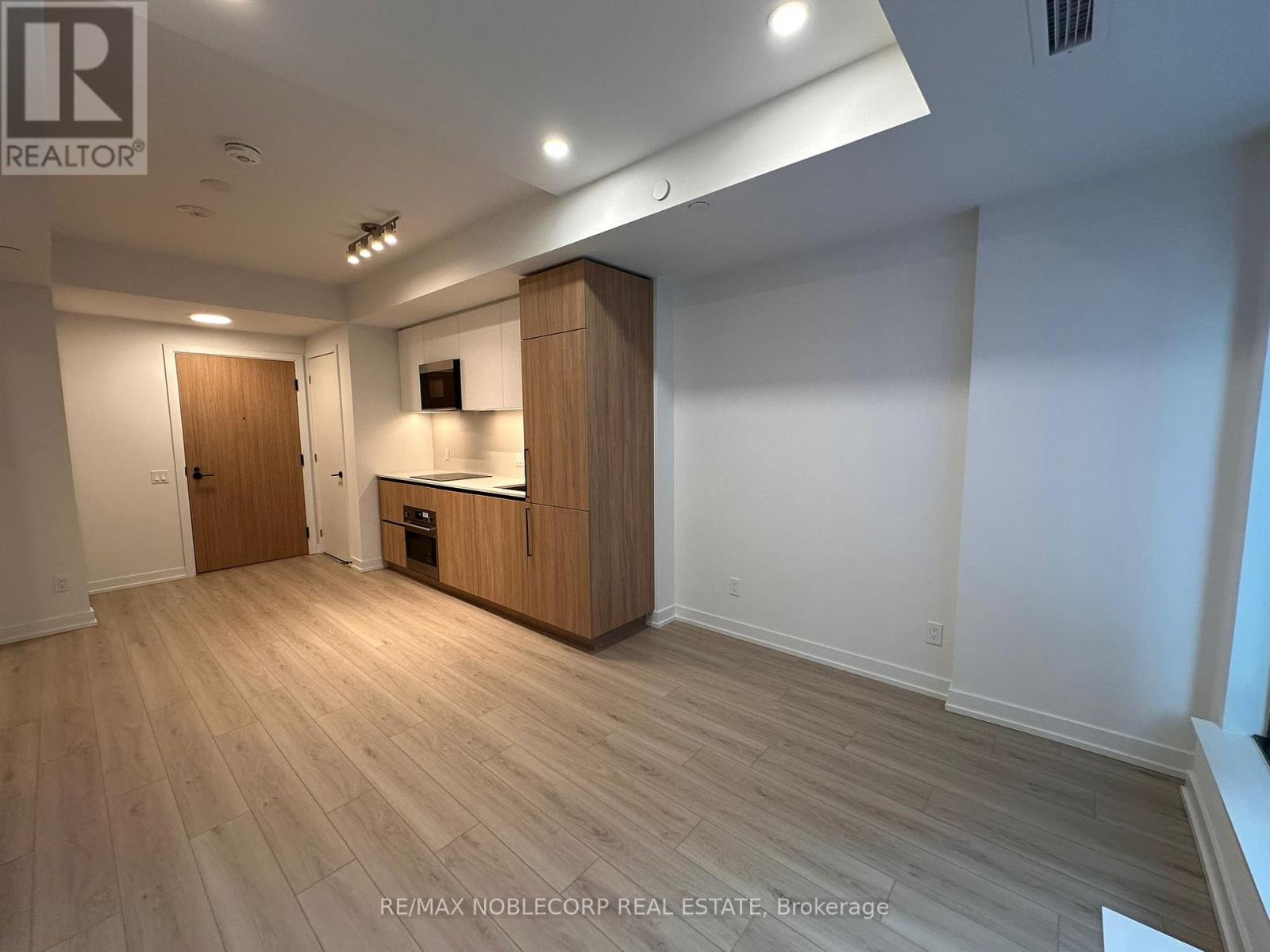 A spacious room with wooden flooring and a cabinet with a television on top.
