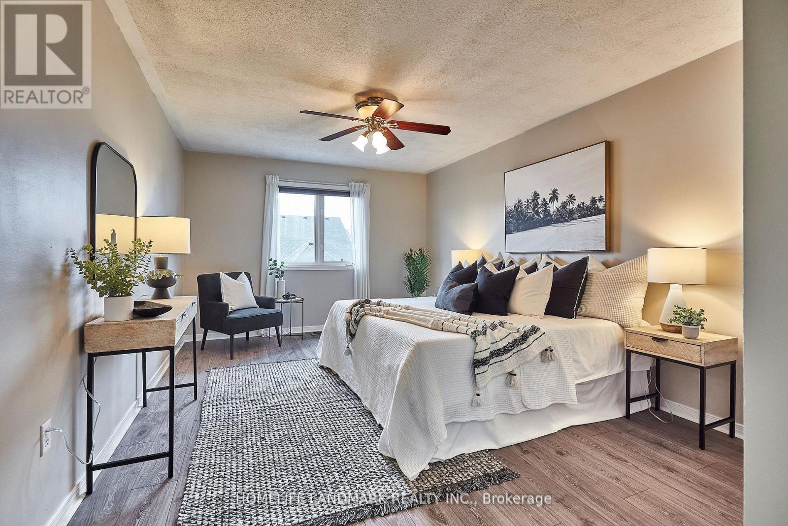 A bedroom with a bed, chair, and ceiling fan.