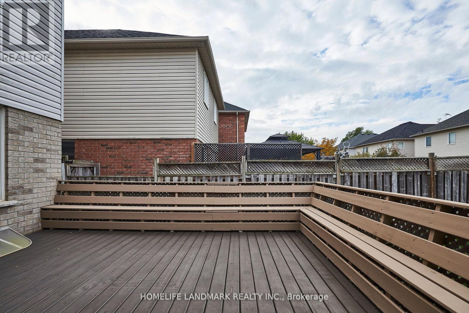 A wooden deck with a bench and a building in the background.