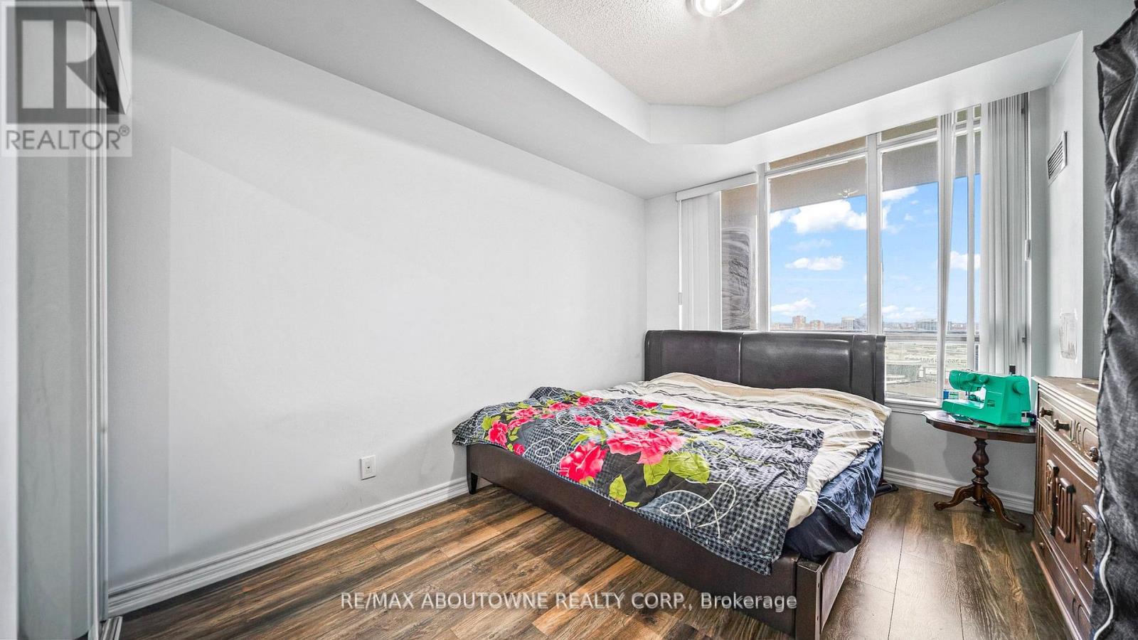 A bedroom with a large bed and a window overlooking a cityscape.