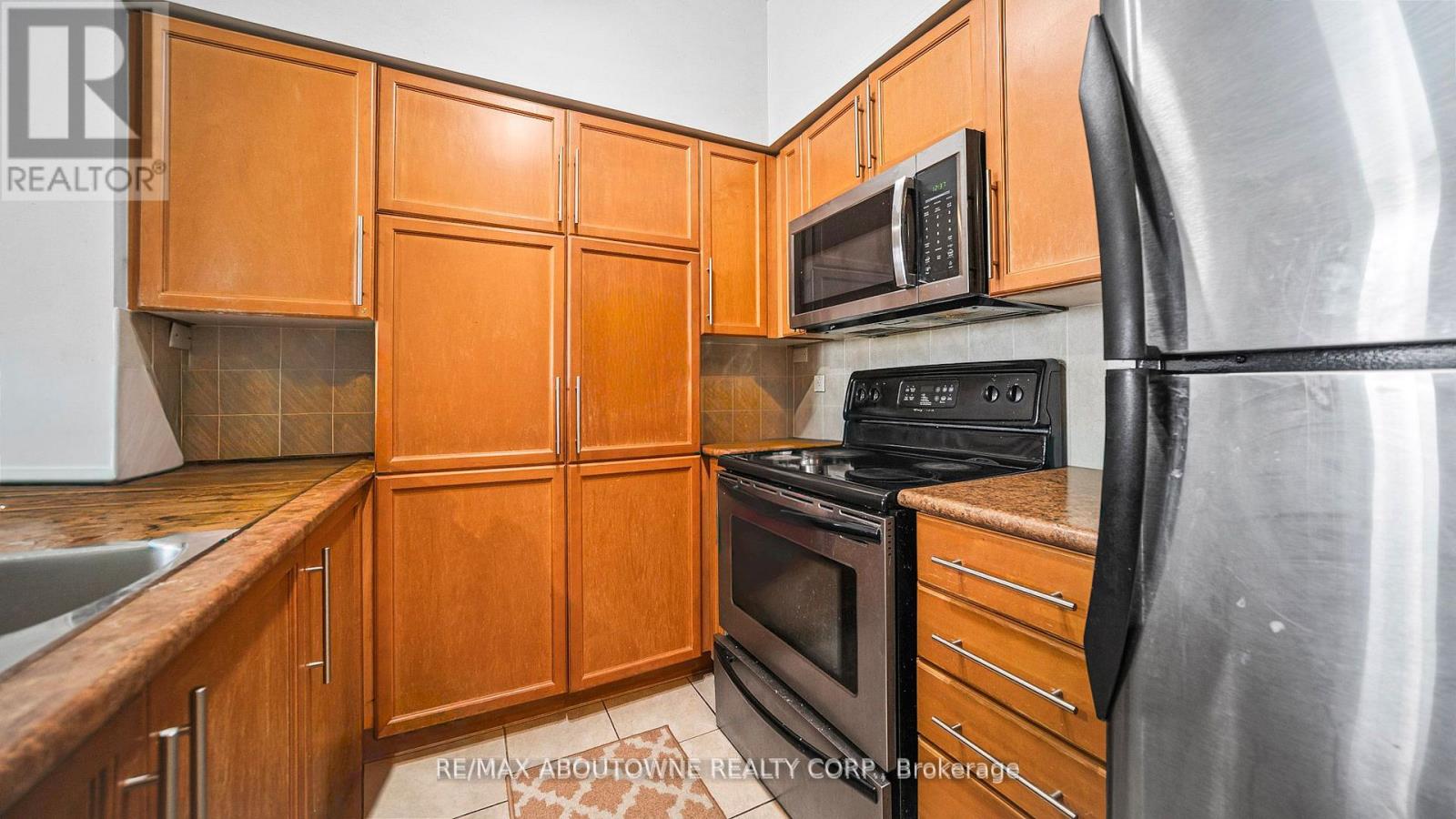A kitchen with wooden cabinets and a stainless steel refrigerator.
