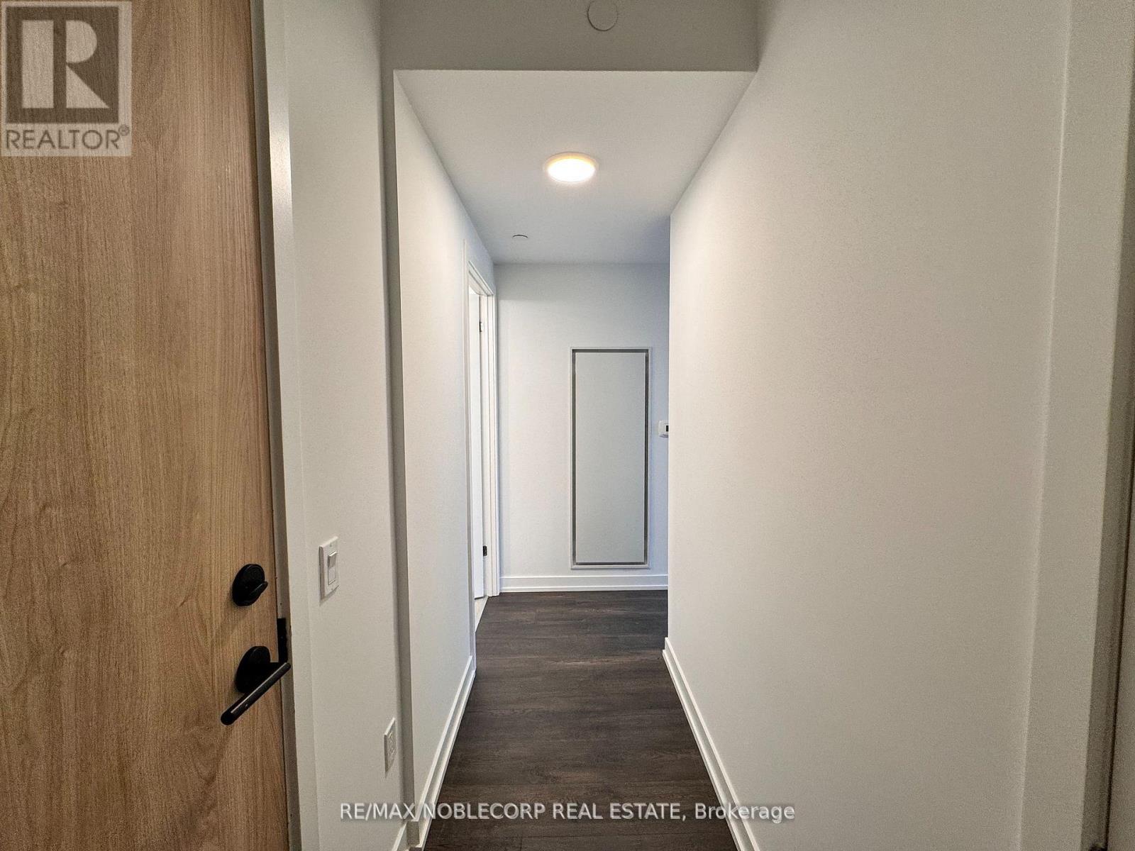 A hallway with a door on the left and a mirror on the right.