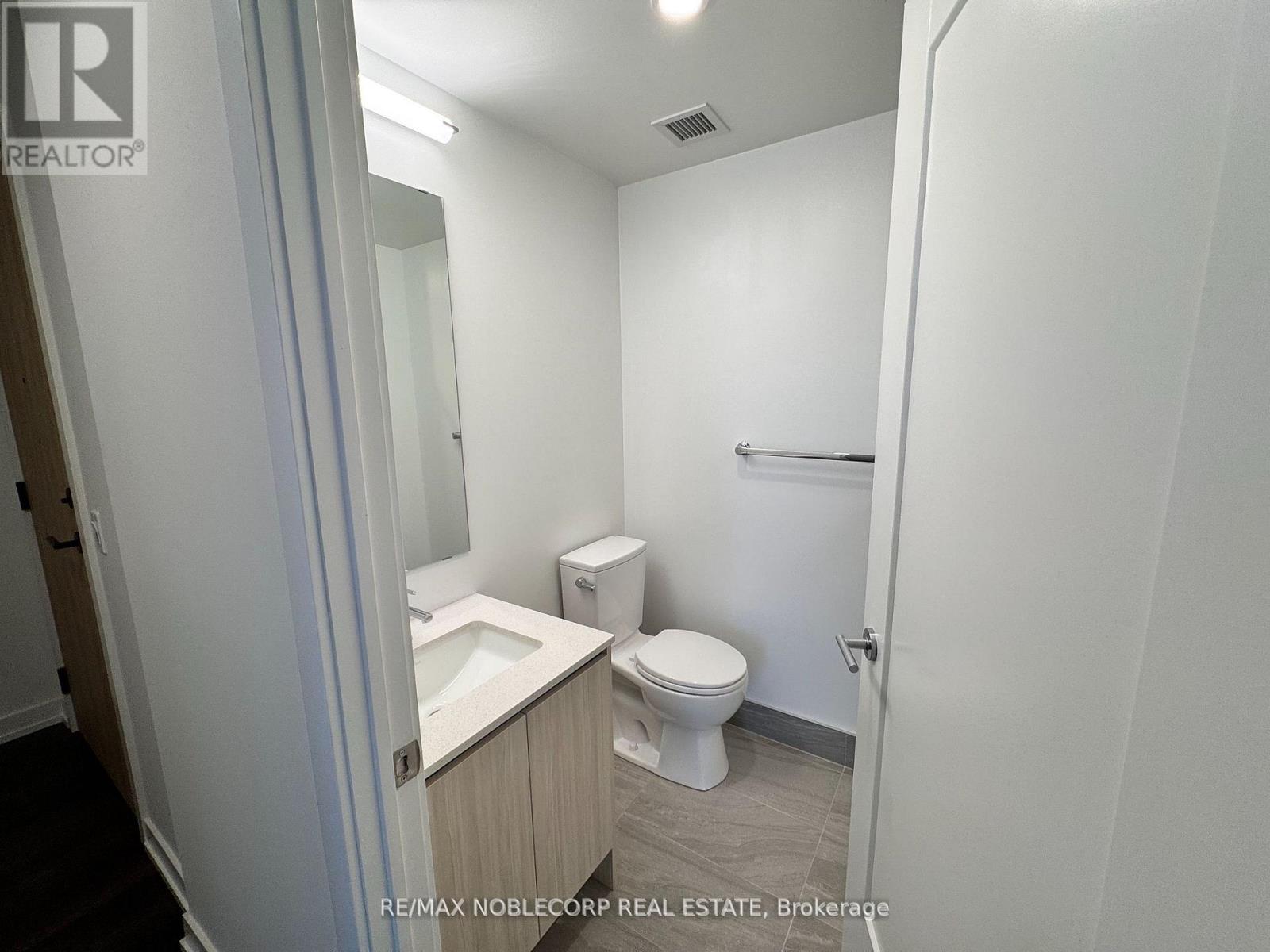 A white bathroom with a toilet, sink, and mirror.