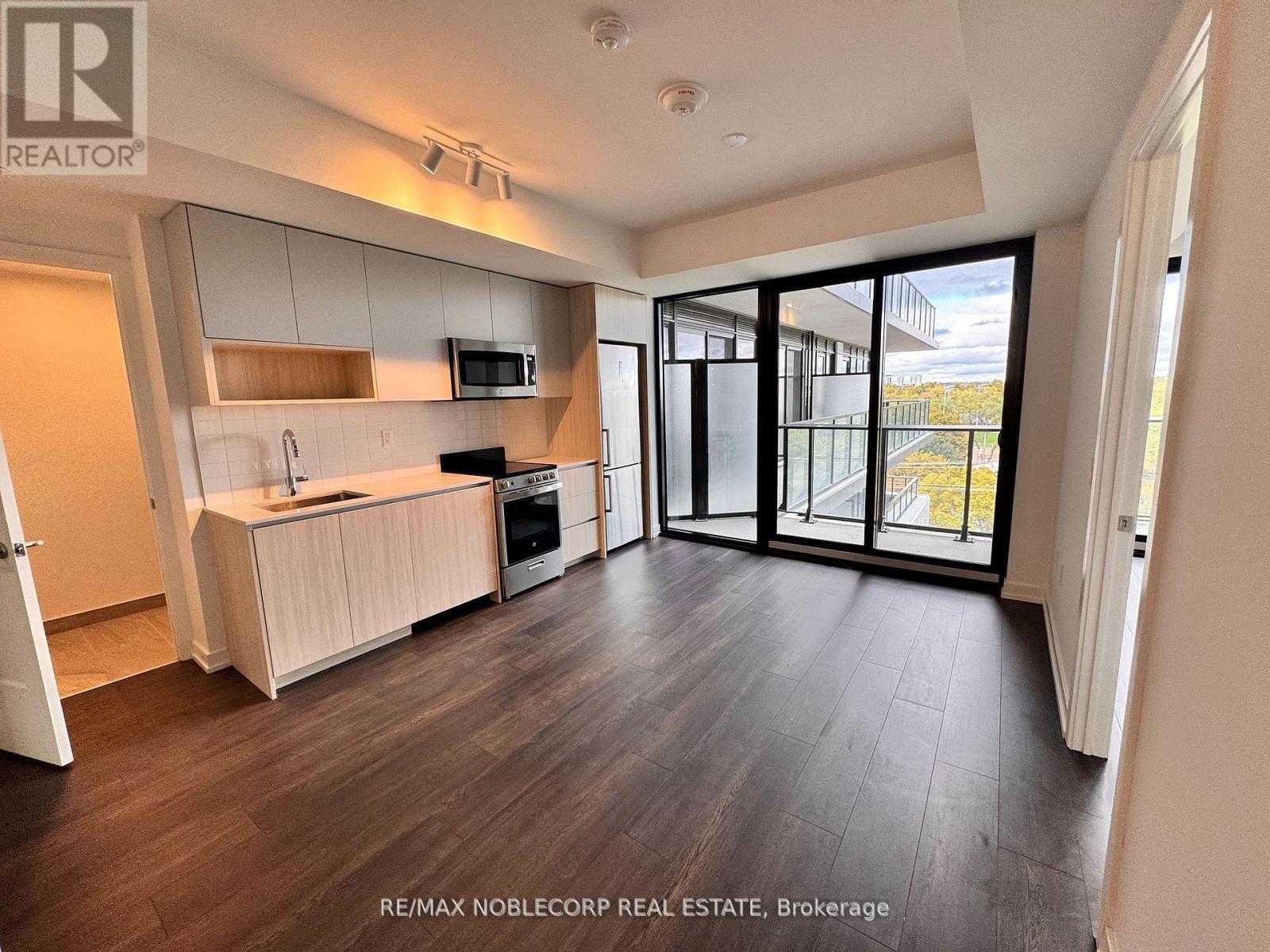 A spacious kitchen with dark wood floors and white cabinetry.