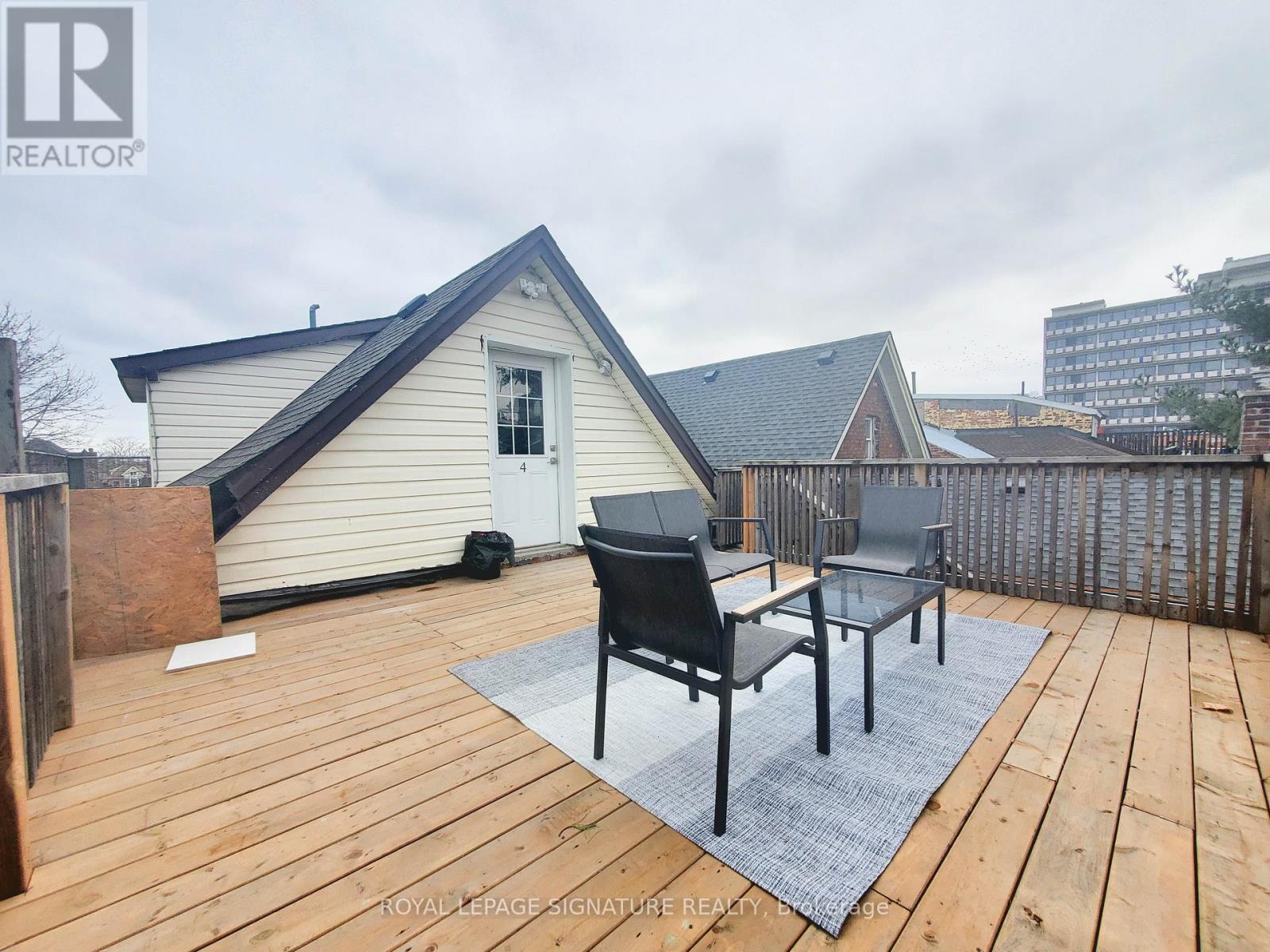 A wooden deck with a table and chairs in front of a house.