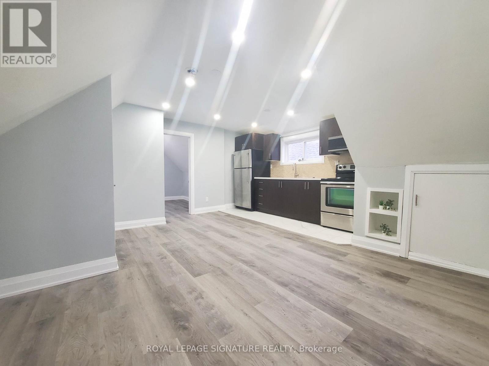 A spacious room with wooden flooring and white walls.