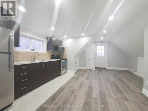 A spacious kitchen with wood flooring and a refrigerator on the left.