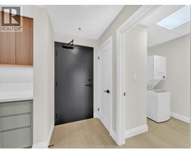A black door is in a white hallway.