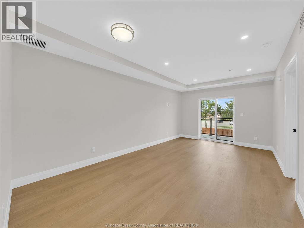A spacious room with wooden flooring and a sliding glass door leading to a balcony.