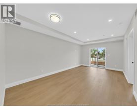 A spacious room with wooden flooring and a sliding glass door leading to a balcony.