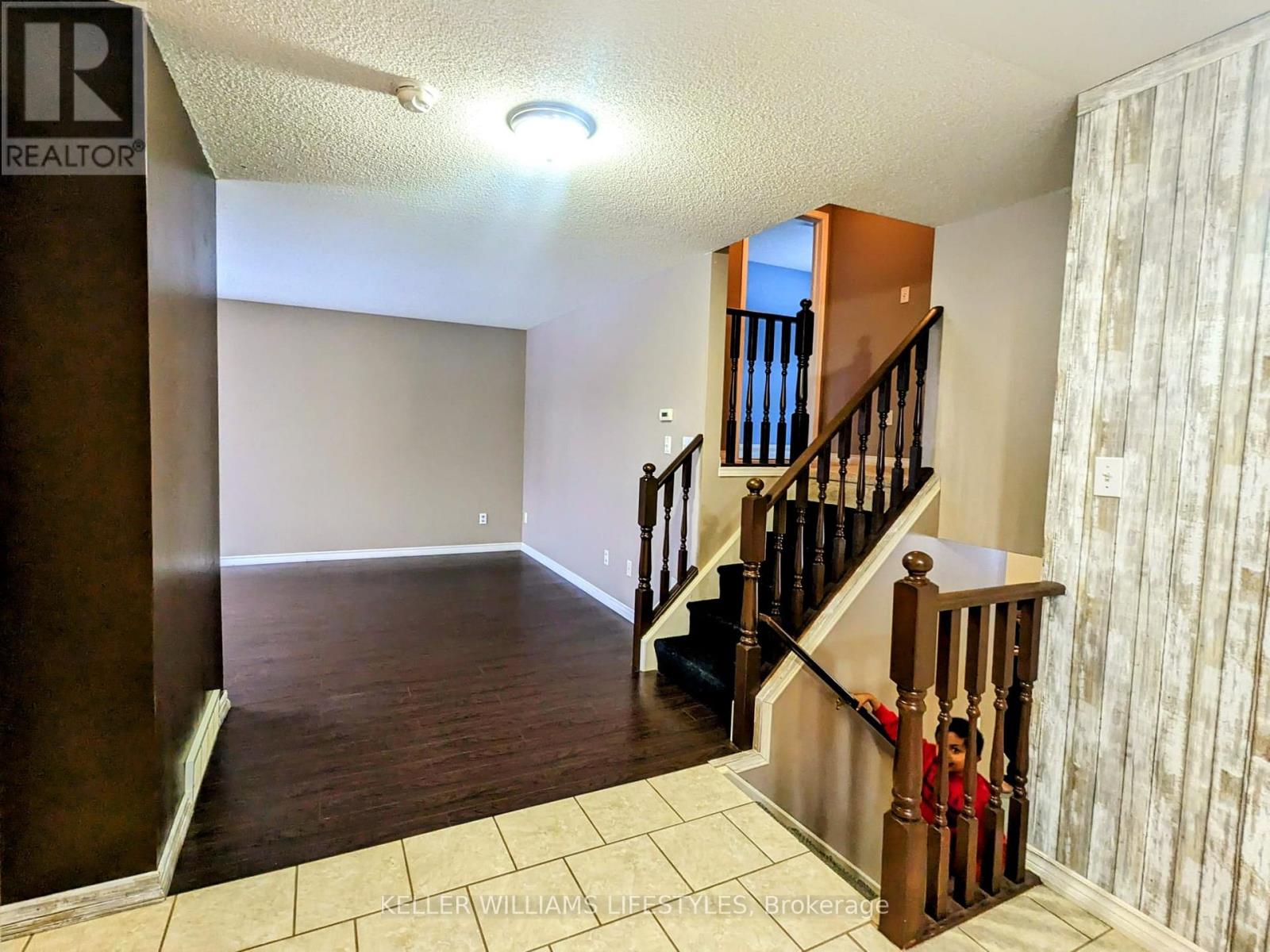 A room with a staircase and a realtor sign.