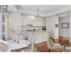 A modern kitchen with white cabinets and a dining table set with vases.